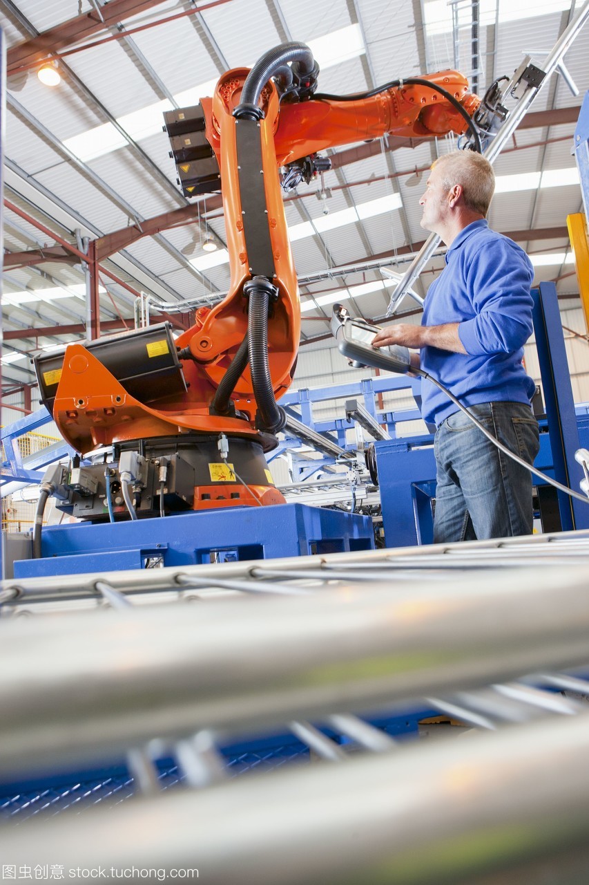 工人在制造工廠的生產(chǎn)線上控制機械吊裝